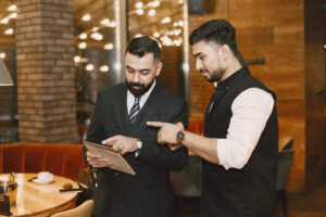 Restaurant manager and staff member reviewing booking or sales data on a tablet inside a modern Indian restaurant.